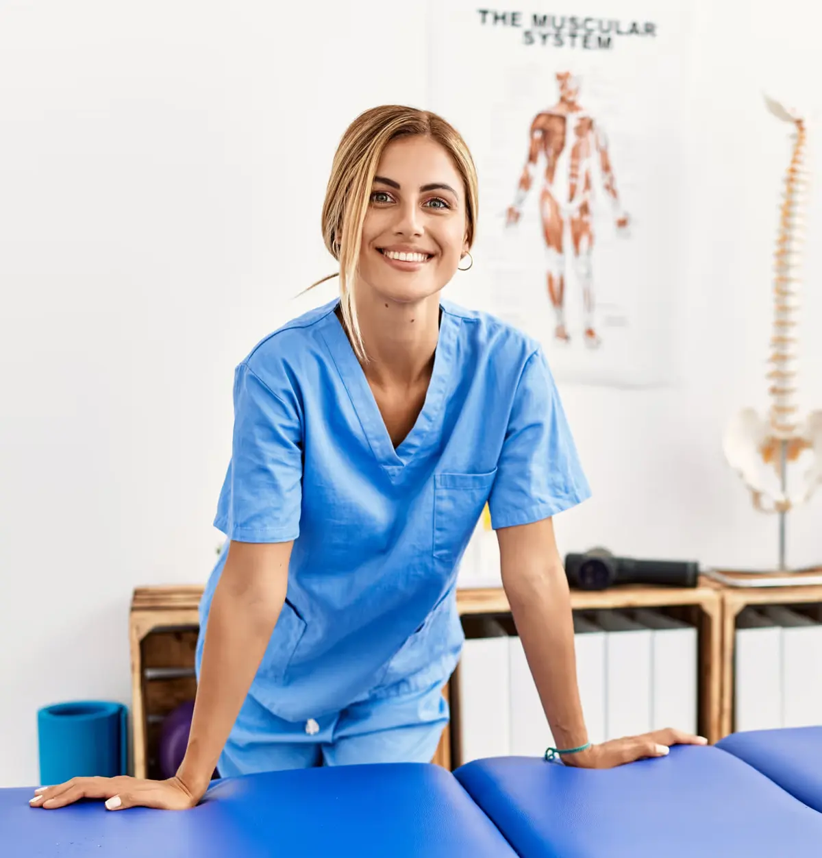 Lächelnde Physiotherapeutin an einer Behandlungsliege